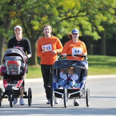 Two female runners and a male runner running with babies in baby strollers