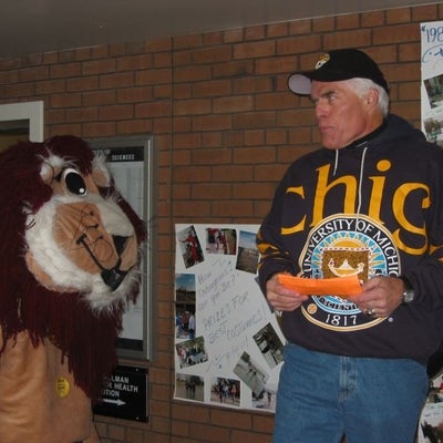 A man looking at a lion mascout skeptically. 