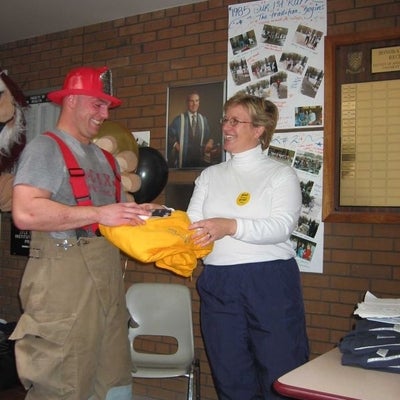 A man in a fire fighter uniform receiving a yellow hoodie