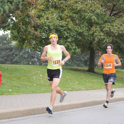 Two male participants running down the road
