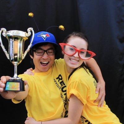 Two students hugging while one holds a little trophy.