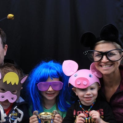 A man and a woman smiling for a photo with three children wearing funny accessories.
