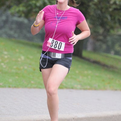 A female runner listening to music through earphones while running the race 