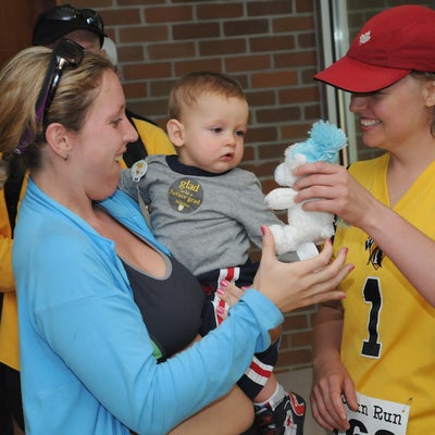 A woman holding her baby receiving a doll from a female staff member during after meeting