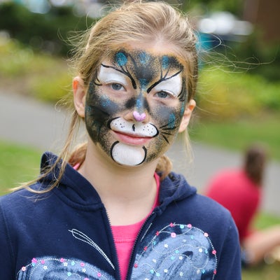 Young girl smiling for a photo with a face painting.