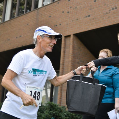 A woman handing a bag over to a running participant.