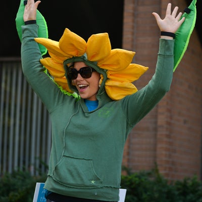 Lady smiling with her hands up dressed as a flower.