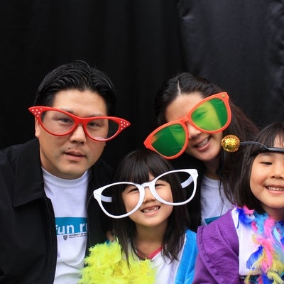 A man, a woman and two young girls wearing funny accessories.