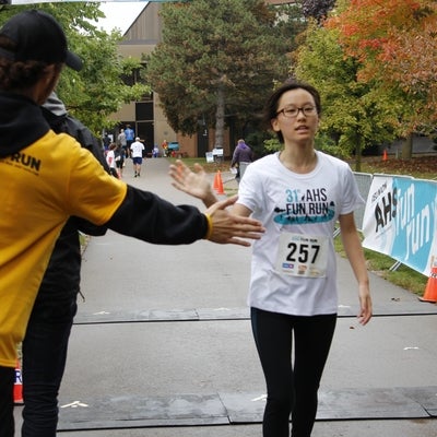 A boy crossing the finish line and giving a volunteer a high five