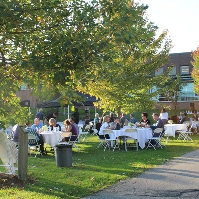 Welcome BBQ with tables of guests on the BMH Green at dusk.