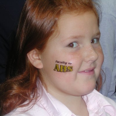 A girl with sticker tatoo written "Faculty of AHS" on her face