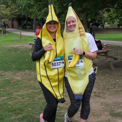 two runners in banana costumes holding bananas
