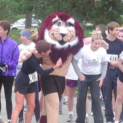 A lion mascot putting arms around two female participants