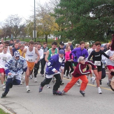 Runners starting the race, three males in the front are riding on roller blades.