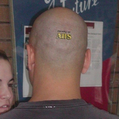 A man with a sticker tatoo written "Faculty of AHS" on back of his head