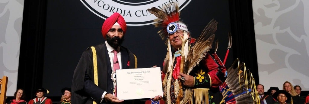 Elder Myeengun Henry receives his honorary doctorate degree from the newly installed Chancellor, Dr. Bachher.