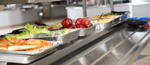 Cafeteria-style food servings, including apples and green vegetables