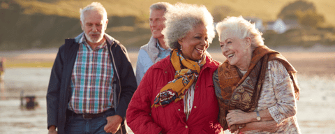 Two older women laughing, two older men walking behind