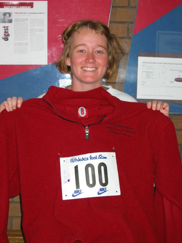 A female participant holding a red sweater with number 100 sticker in the middle
