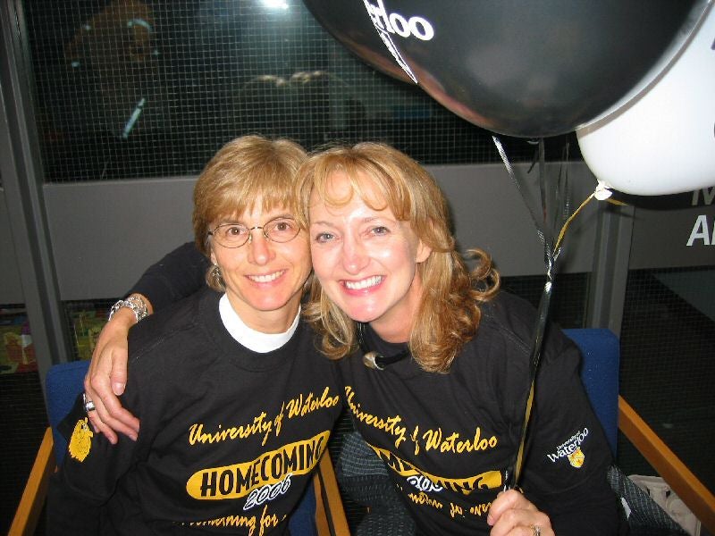 Two females in University of Waterloo t-shirts putting arms around each other's shoulders
