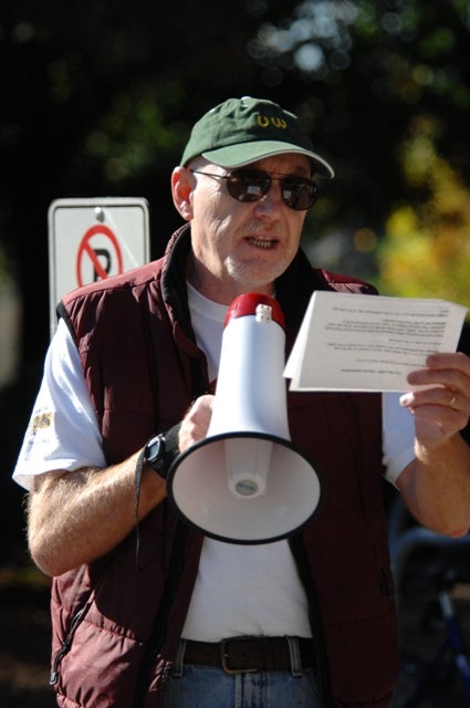 A man reading a paper out loud through a megaphone