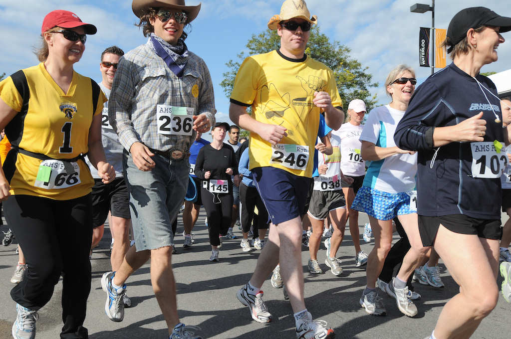 View of people jogging while focusing two male runners wearing cowboy hats