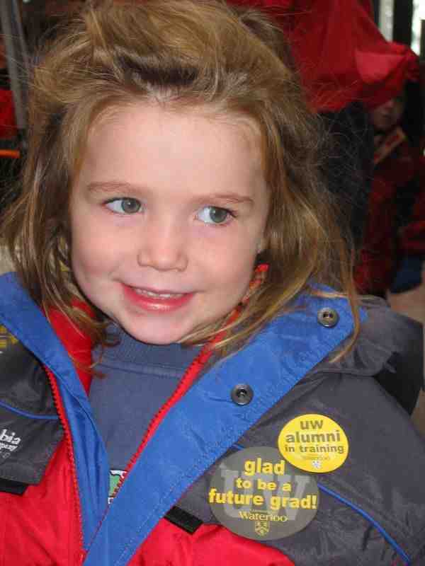 A girl smiling with two University of Waterloo badges on her jacket