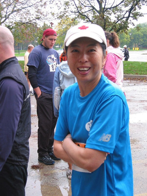 A female runner with a white hat and blue t-shirt looking towards the camera