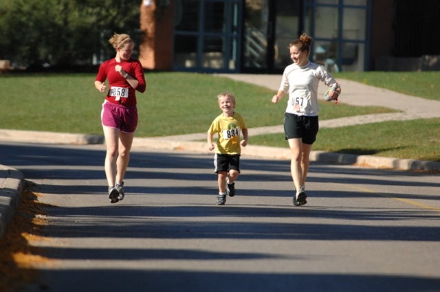 Two females running with a little boy in the middle 
