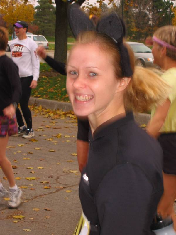 A focus of a woman with cat ears headband during stretching with other people