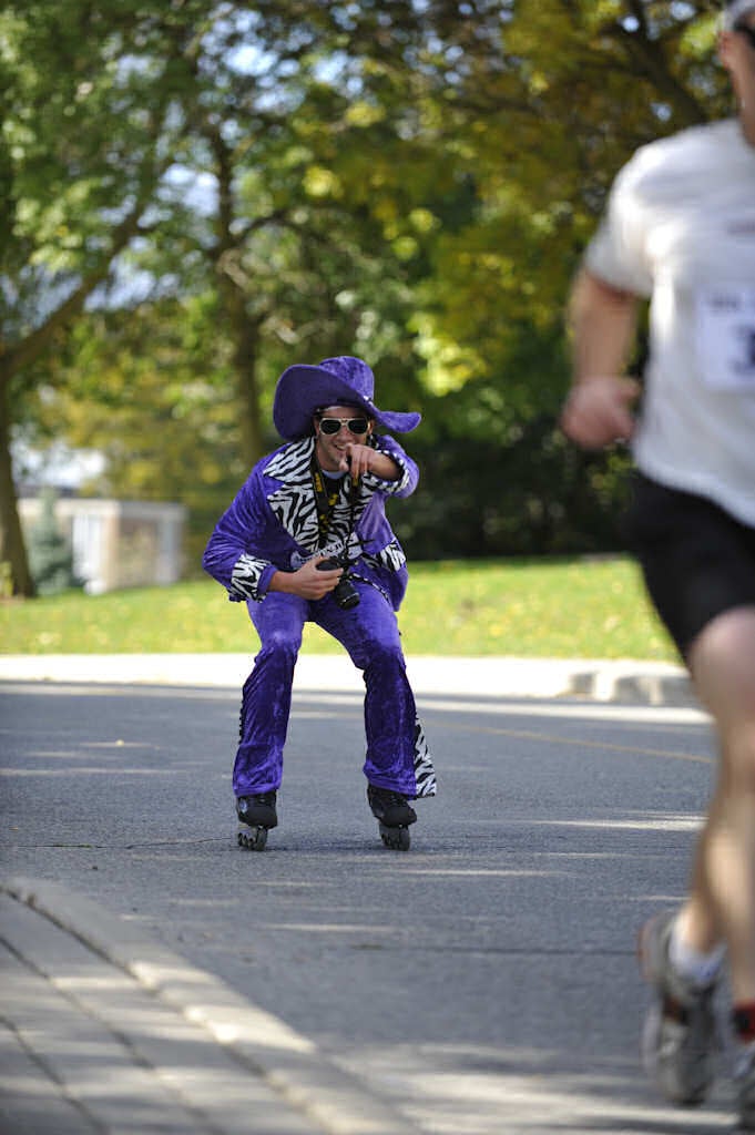 A male participant dressed as disco dancer on roller blades pointing to the camera