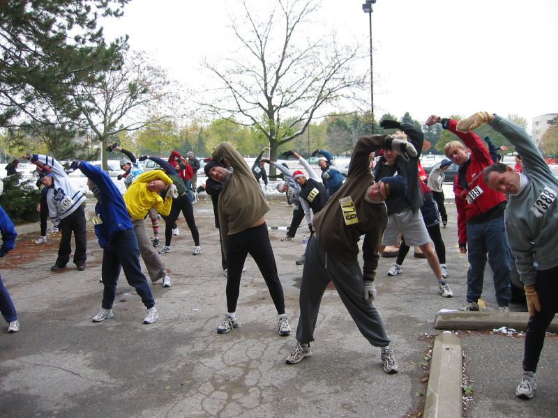 Runners stretching outside near a parking lot 