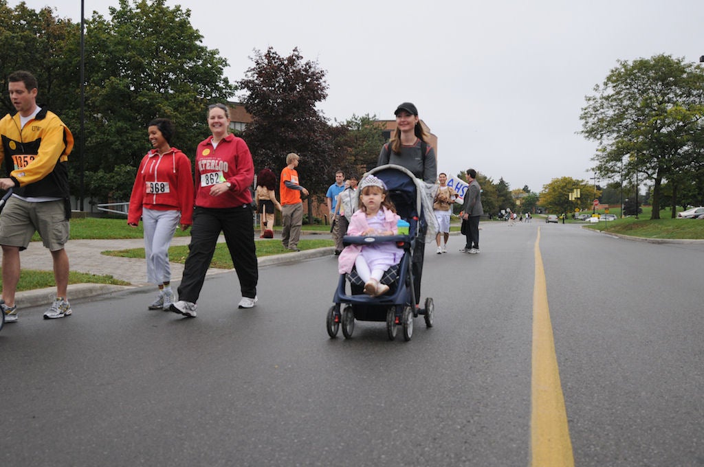People in the race while focusing on a woman with her baby in a baby stroller