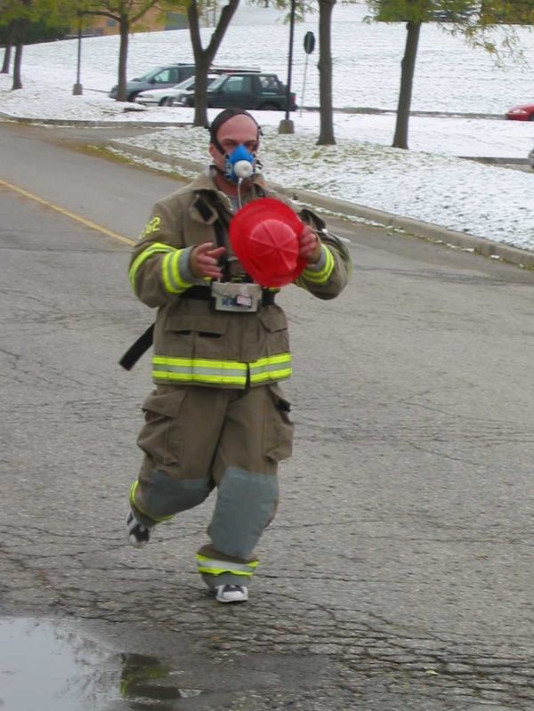 A male dressed as a firefighter running down the road. 