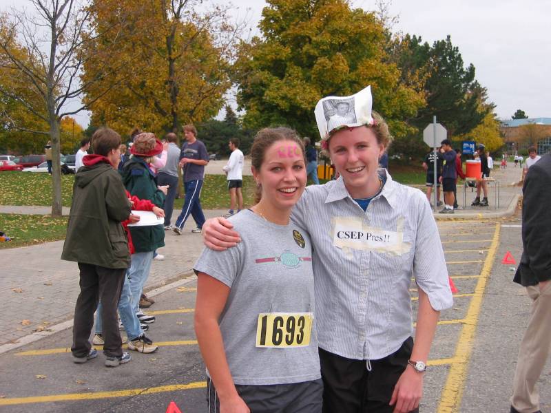 Two female runners with grey shirts with pictures and letter stuck on top