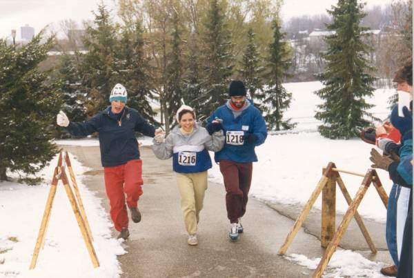 Two male runners and one female runner reaching the finish line together.