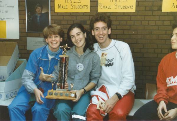 Female holding and pointing at trophee, sitting with her friends.