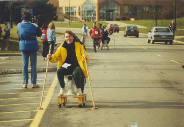 A girl riding on a toilet cart.