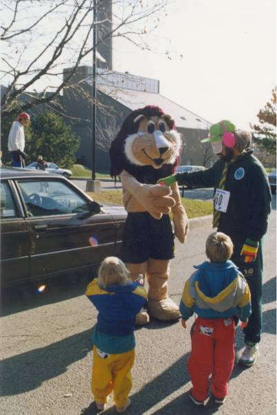 A lion mascot shaking hands with a man