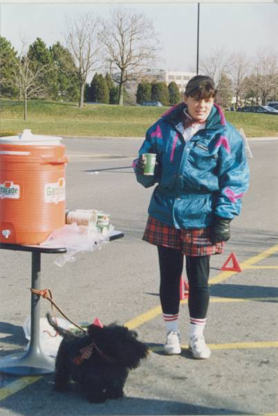 A girl holding a cup of water for the runners at water station.