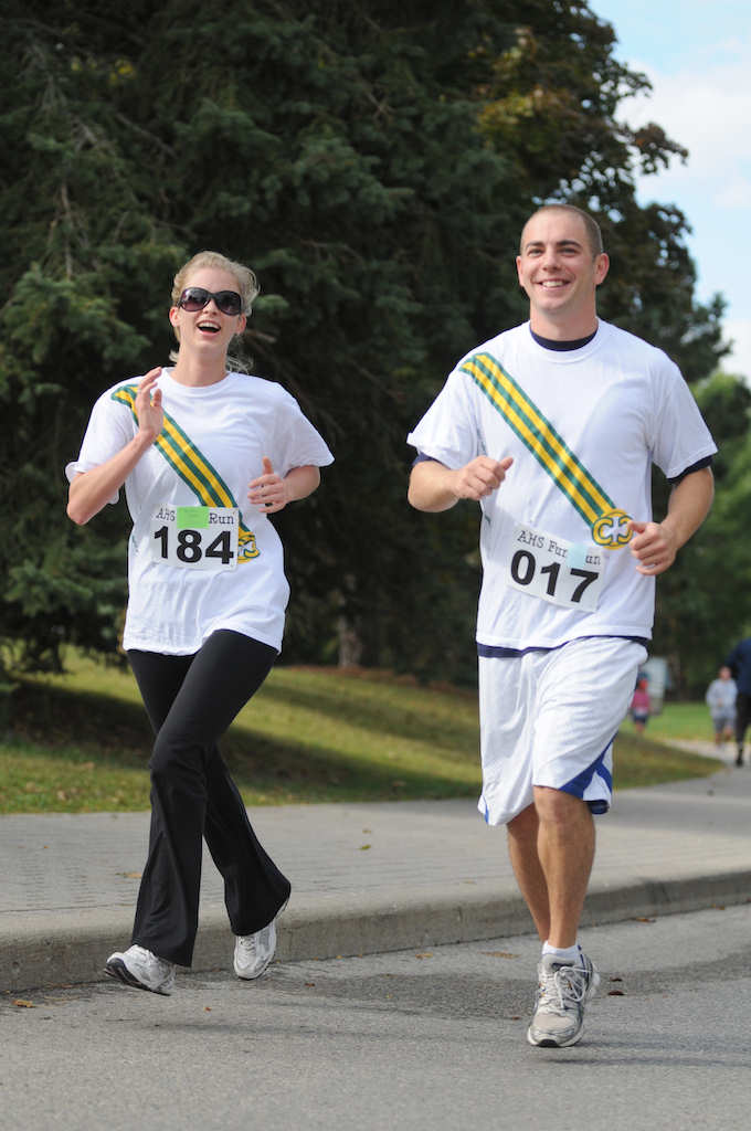 Two runners wearing matching white shirts with diagonal stripes