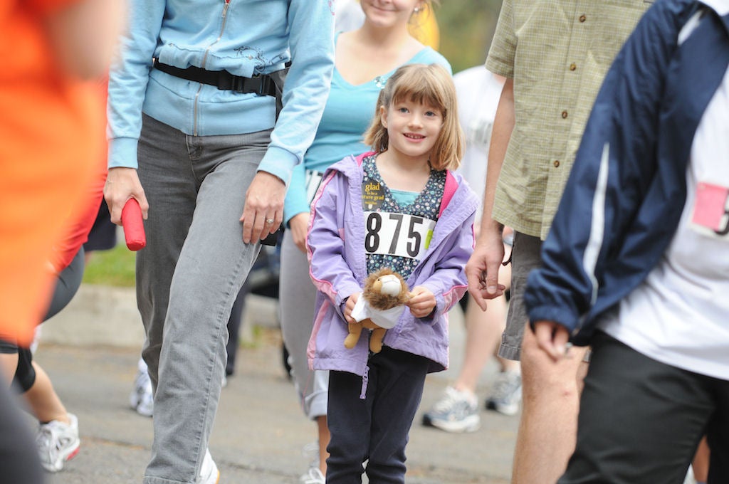 A little girl holding a lion doll participating the race with other adults