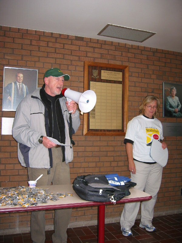 A man talking through a megaphone in front of the room and a woman standing beside him