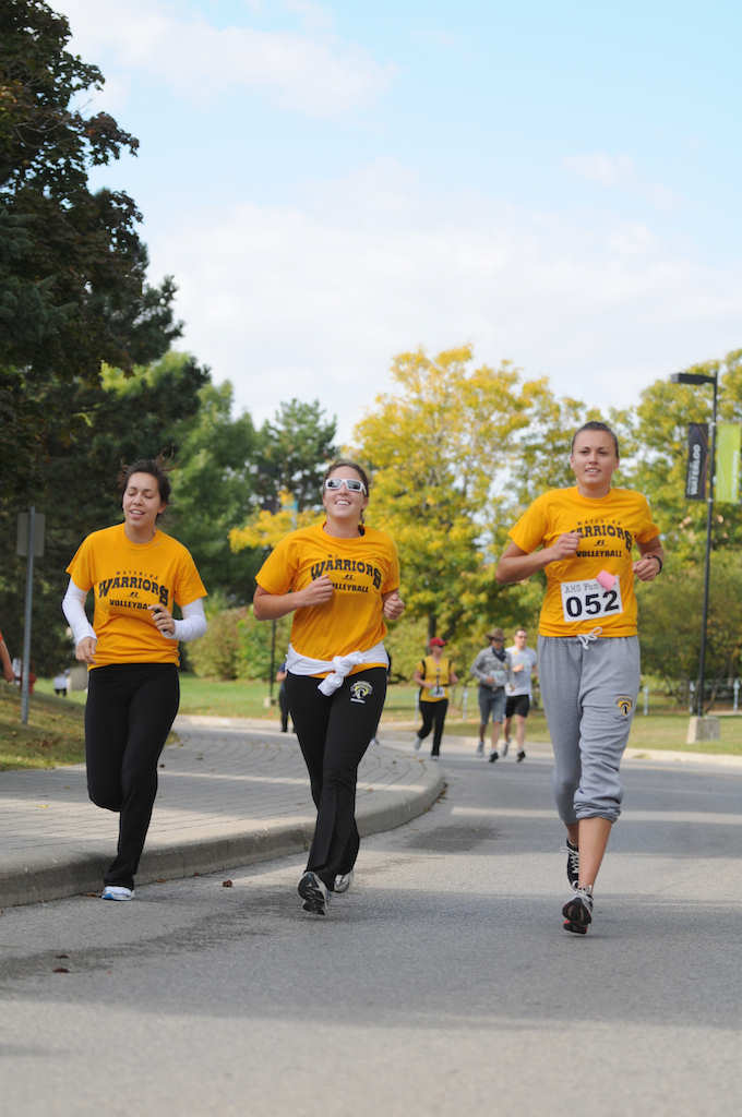 Three females of a University of Waterloo volleyball team running together