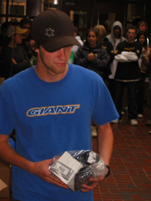 Man wearing a black hat and blue shirt holding a package in a plastic bag