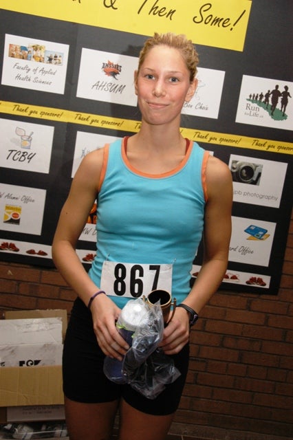 A female runner holding her trophee and a package in a plastic bag