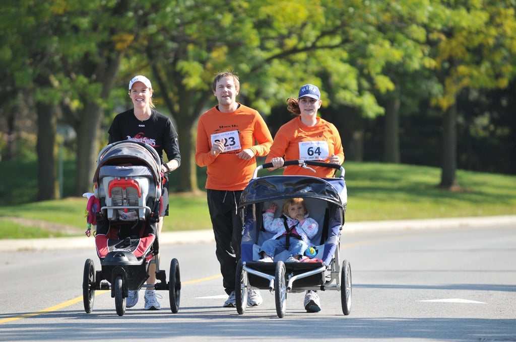 Two female runners and a male runner running with babies in baby strollers