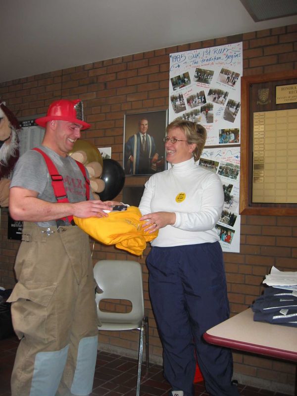 A man in a fire fighter uniform receiving a yellow hoodie