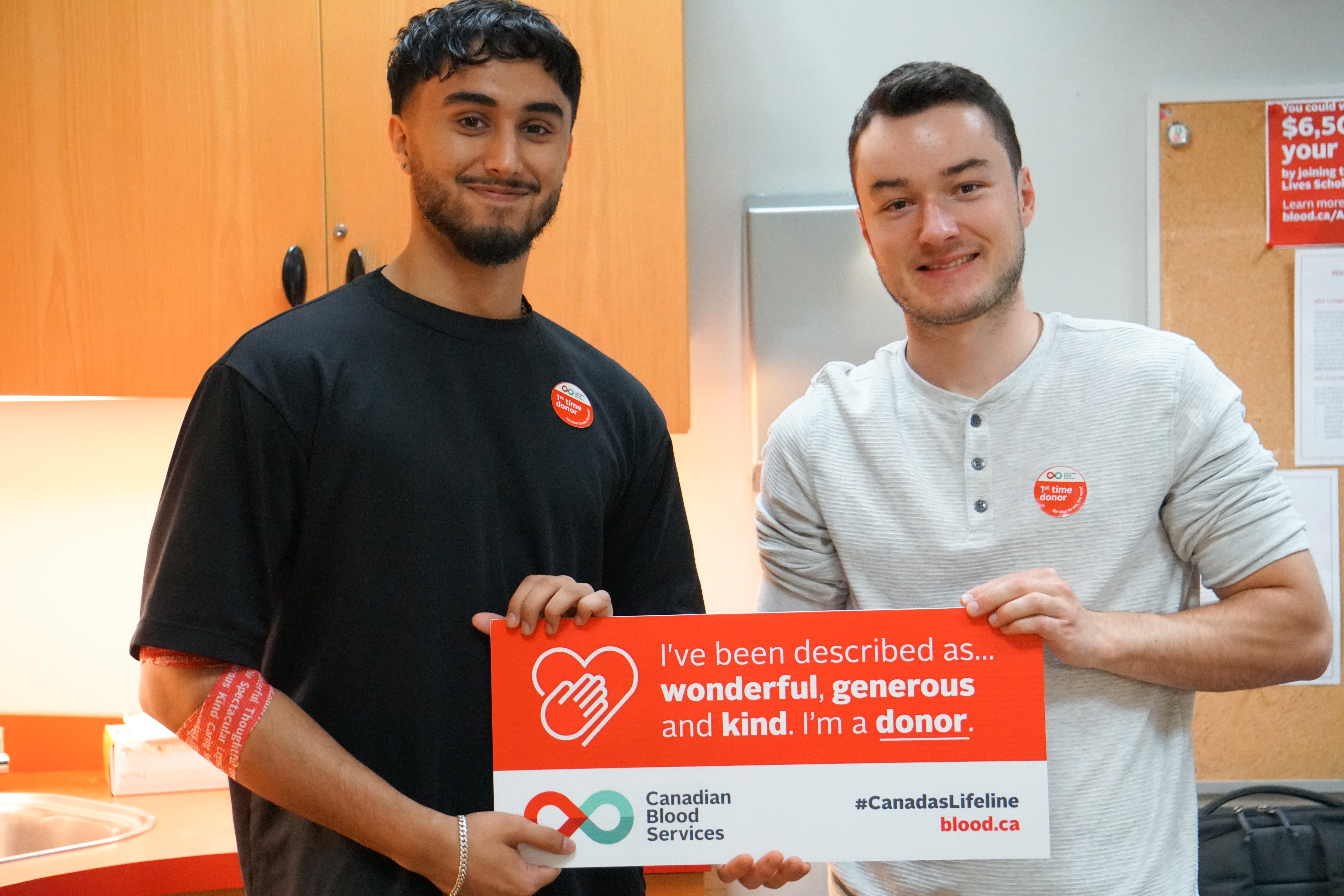 Two Waterloo students who have just donated blood hold up a sign that reads: "I've been described as wonderful, generous and kind. I'm a donor."