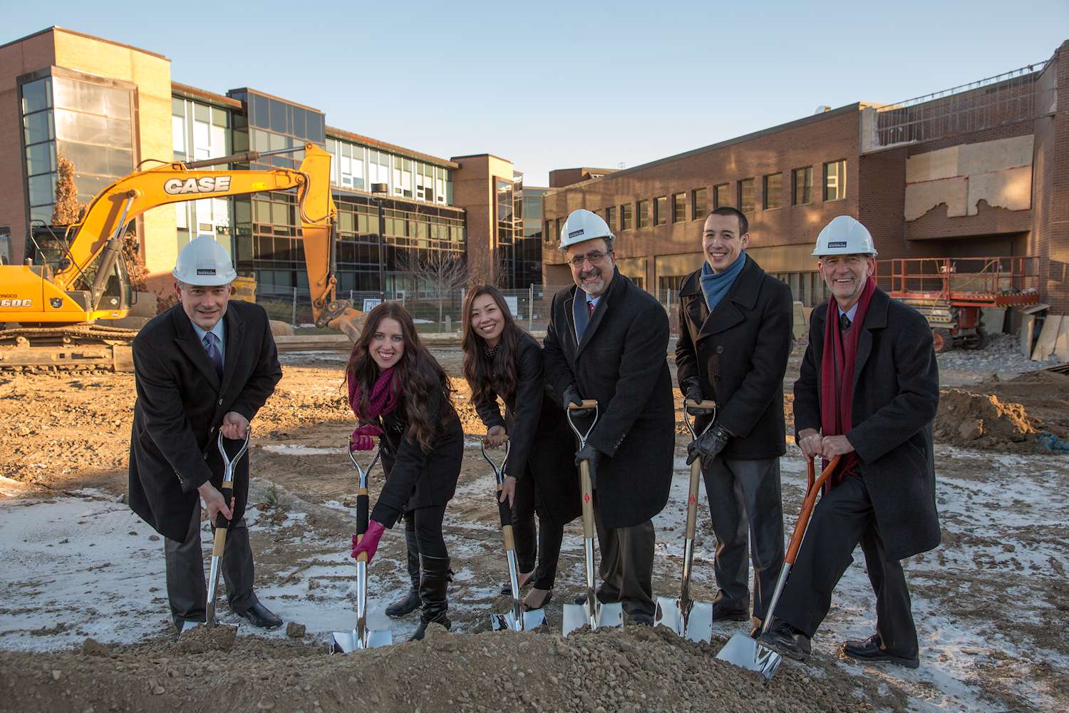 The Dean, President and guests place shovels in ground on construction site.